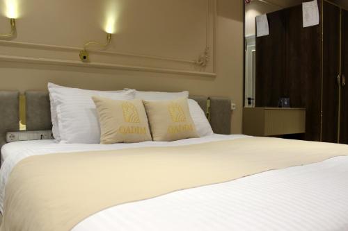 a large bed with white sheets and pillows at Qadim Hotel in Samarkand