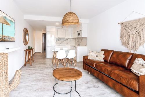 a living room with a brown leather couch and a table at Shambhala Fuerteventura in Parque Holandes