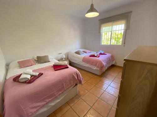 2 Betten in einem Zimmer mit rosa Bettwäsche in der Unterkunft Finca el Pereo in Alhaurín el Grande