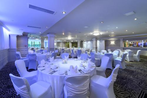 a room with white tables and white chairs and tablesearcher at Glynhill Hotel & Spa near Glasgow Airport in Paisley