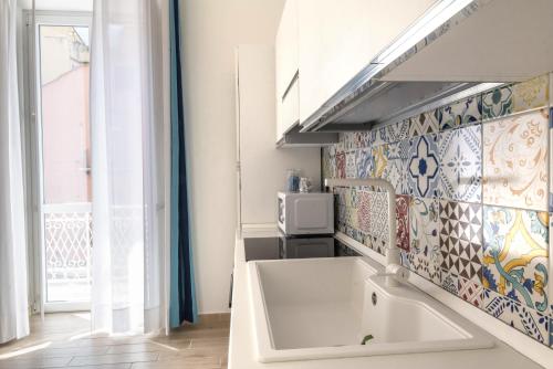 een keuken met een witte spoelbak en een tegelmuur bij Mya Home Luxury Apartments in Castellammare di Stabia