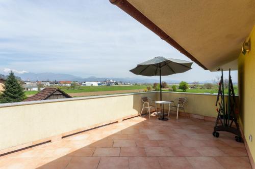 a balcony with an umbrella and a table and chairs at Apartma Majdas in Loka pri Mengšu