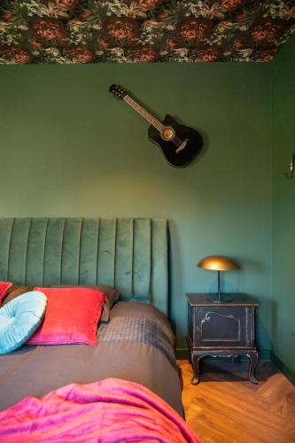 a guitar on a green wall next to a bed at The Music Suites in Bruges