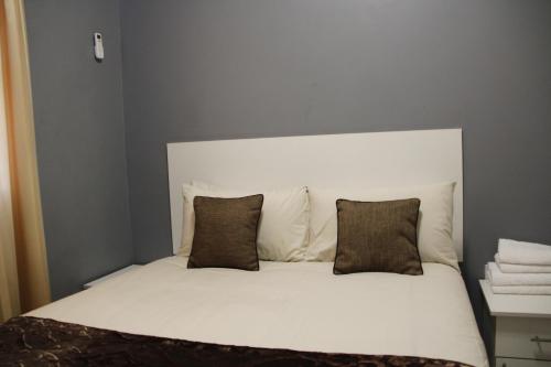 a white bed with two pillows on top of it at Asante Apartments in Livingstone