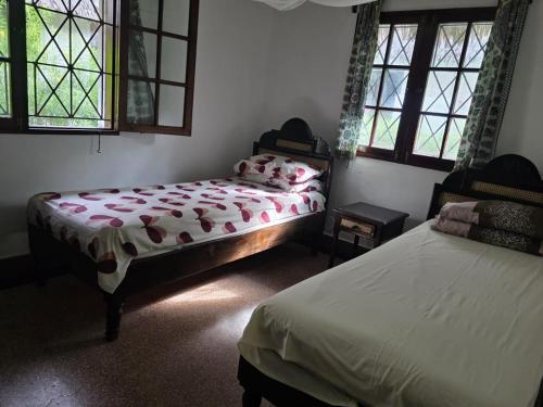 a bedroom with two beds and two windows at Karibuni, Villa 107, Beachfront Stay with Restaurant, Pool & Bar in Malindi
