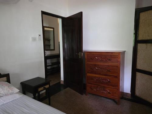 a bedroom with a dresser and a bed and a mirror at Karibuni, Villa 107, Beachfront Stay with Restaurant, Pool & Bar in Malindi