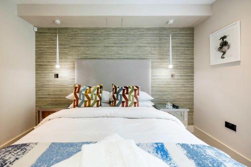 a bedroom with a large white bed with striped pillows at The Bohemian Rhapsody, Hampstead - by Out of office Lifestyle in London