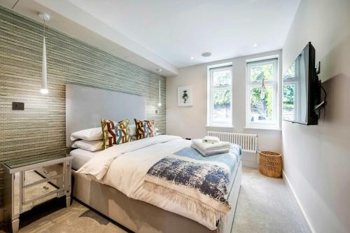 a bedroom with a bed and a flat screen tv at The Bohemian Rhapsody, Hampstead - by Out of office Lifestyle in London