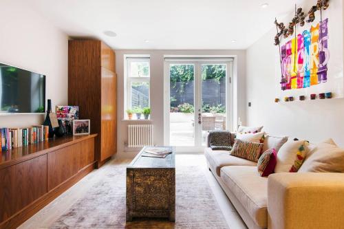 a living room with a couch and a tv at The Bohemian Rhapsody, Hampstead - by Out of office Lifestyle in London