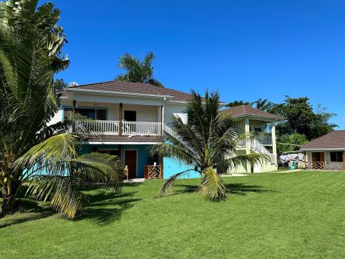 a house with a palm tree in front of it at Yoga Dreams Negril in Negril