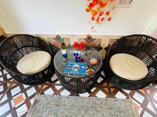 a table with three chairs and a bottle of wine at Hotel Brownie River View in Kasol