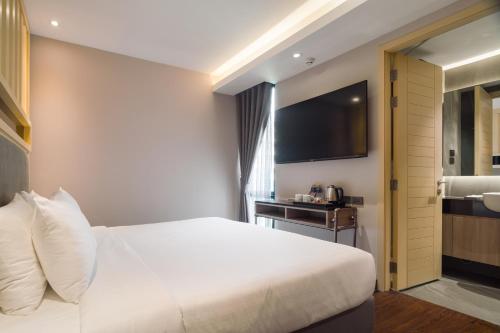 a hotel room with a white bed and a television at T2 The Portal Sukhumvit in Bangkok