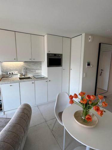 a kitchen with a table with a vase of flowers on it at Luxe studio/suite met zeezicht en volle zon in Knokke-Heist