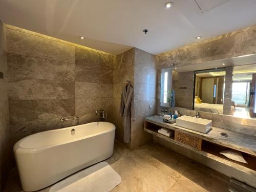 a bathroom with a tub and a sink and a mirror at Renaissance Dhaka Gulshan Hotel in Dhaka