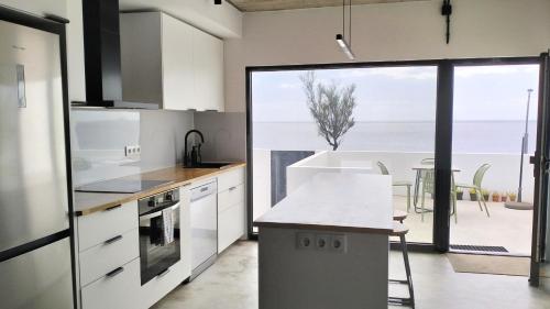 a kitchen with white cabinets and a view of the ocean at Roque Ocean House - Atlantic Serenity Escape in São Roque
