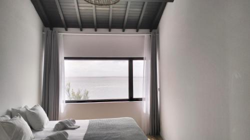 a bedroom with a bed and a large window at Roque Ocean House - Atlantic Serenity Escape in São Roque