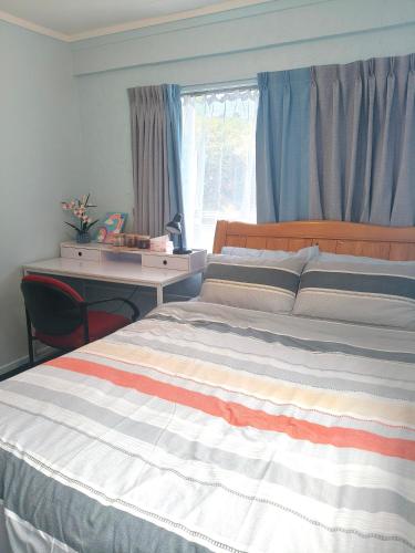 a bedroom with a bed with a desk and a window at Cozy Bedroom in Tauranga in Tauranga