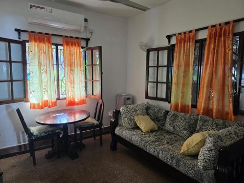 a living room with a couch and a table and windows at Karibuni, Villa 107, Beachfront Stay with Restaurant, Pool & Bar in Malindi