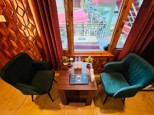 two chairs and a table in a room with a window at Hotel Brownie River View in Kasol