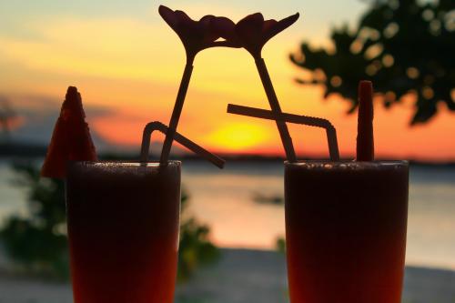 two cocktails sitting on a table with the sunset in the background at Salili Bungalow in Gili Air