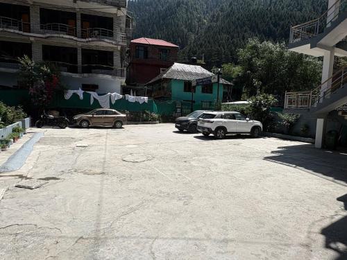 a parking lot with cars parked in front of buildings at Hotel Brownie River View in Kasol