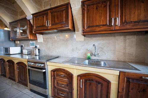a kitchen with wooden cabinets and a sink at 5 Bedroom Holiday Farmhouse with Private Pool in Għarb