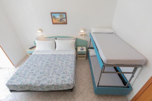 a small room with two beds and a desk at Hotel Lauretta in Bellaria-Igea Marina