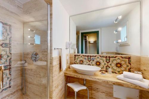 a bathroom with a sink and a glass shower at Aegusa Hotel in Favignana