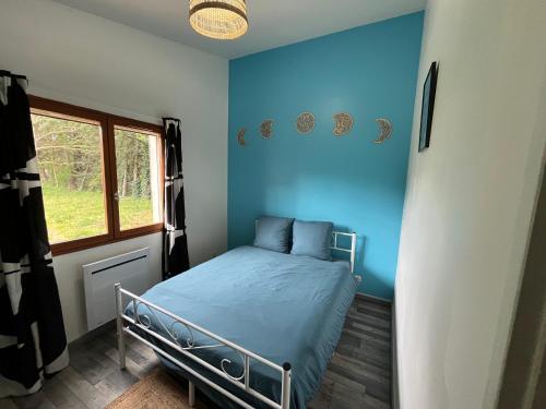 une chambre avec un lit aux murs bleus et une fenêtre dans l'établissement Maison Nature, à Simiane-Collongue
