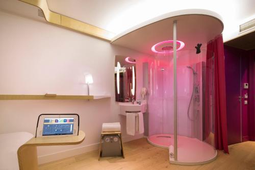 a pink bathroom with a shower and a sink at Nomad Paris Roissy CDG in Le Mesnil-Amelot