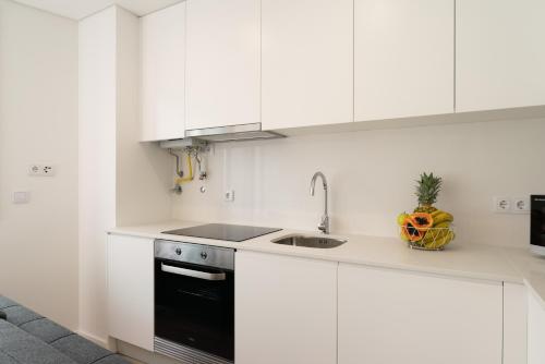 une cuisine blanche avec un évier et une cuisinière dans l'établissement HostWise Cozy Studio with Balcony and Garage, à Leça da Palmeira