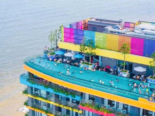 a building with a swimming pool next to the water at Flamingo Hai Tien in Nam Khê