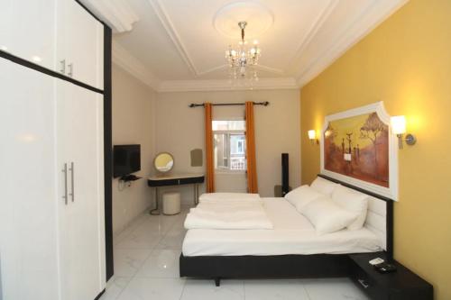 a bedroom with a large white bed and a chandelier at RAP Appart 302 avec piscine in Douala