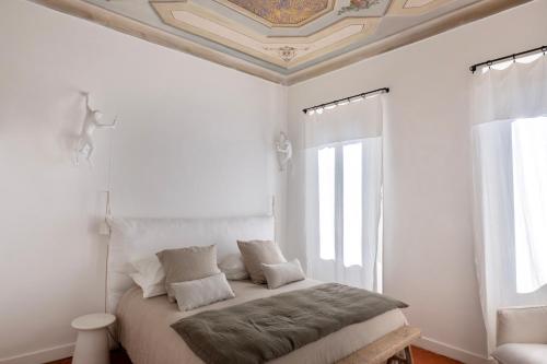 a white bedroom with a bed with a coffered ceiling at La Bâtisse en Blanc in Golfe-Juan