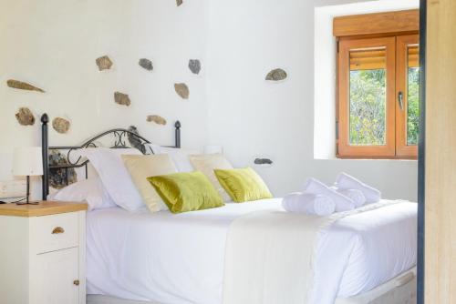 a white bedroom with a white bed with yellow pillows at Quinta entre palmeras in Santa Brígida