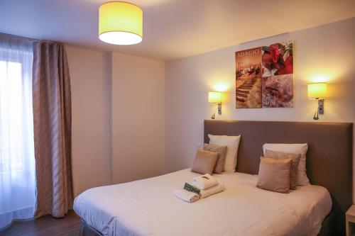 a hotel room with a bed with two pillows at Hôtel CASABELLA Cannes Mouans Sartoux in Mouans-Sartoux