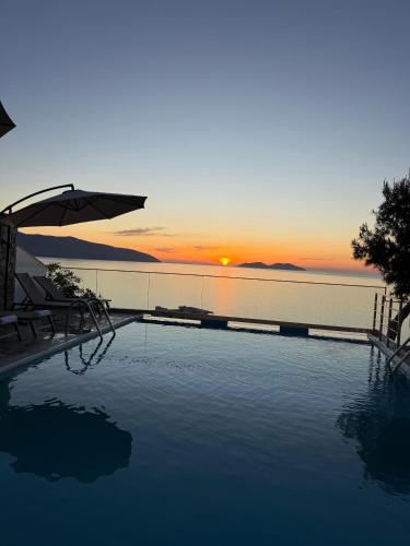 a swimming pool with a sunset in the background at Vila Dena in Vlorë