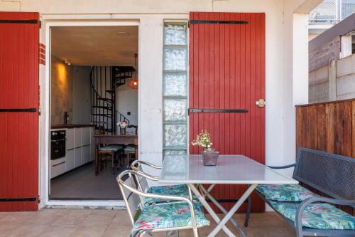 une table et des chaises dans une cuisine avec des portes rouges dans l'établissement Villa Etchola - Moutchic -3 étoiles, à Lacanau