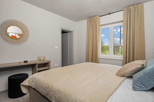 a bedroom with a bed and a desk and a window at Villa Nori Labin in Labin