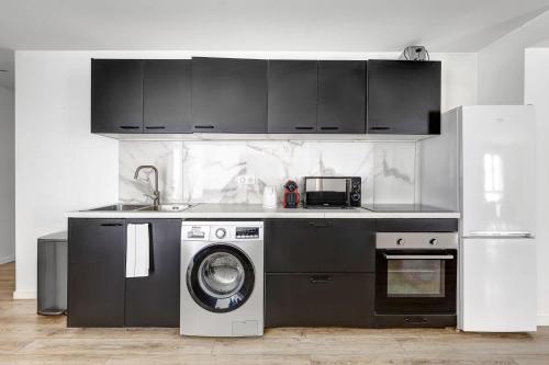 une cuisine avec un lave-linge et un micro-ondes dans l'établissement Sejour elegant aux Buttes Chaumont pour 12 pers, à Paris