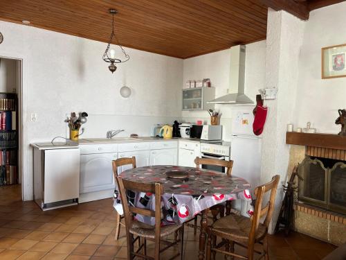 une cuisine avec une table et des chaises et une cuisine avec des appareils blancs dans l'établissement Grande maison de vacances, à Saint-Georges-dʼOléron
