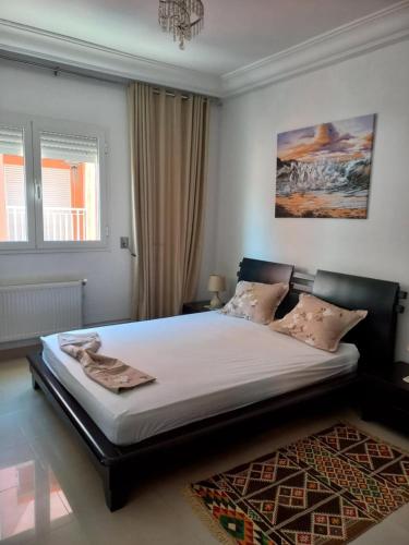 a bedroom with a large bed with white sheets and a rug at Beautiful Apartment in Kantaoui Sousse tourist area in Hammam Sousse