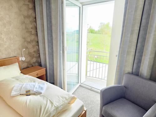 a bedroom with a bed and a chair and a window at Gasthof goldener Engel in Kemnath