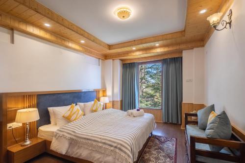 a bedroom with a bed and a chair and a window at Hostie Heaven View - 3BHK Duplex with Terrace, Mashobra in Mashobra