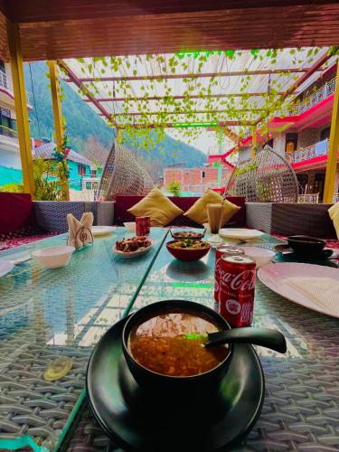 a table with bowls of food and drinks on it at Hotel Brownie River View in Kasol
