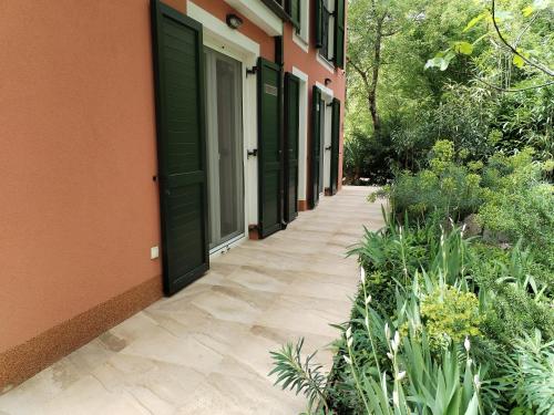 a walkway next to a building with green doors at The Forest House Krk 1 in Kras