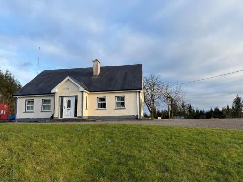 a white house with a black roof on a grass field at #1 - Family or Triple Room in Ballinamore, Leitrim in Ballinamore