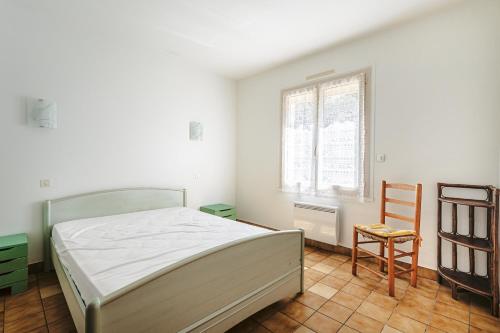 une chambre avec un lit, une chaise et une fenêtre dans l'établissement Maison proche plage et centre ville, à Saint-Trojan-les-Bains
