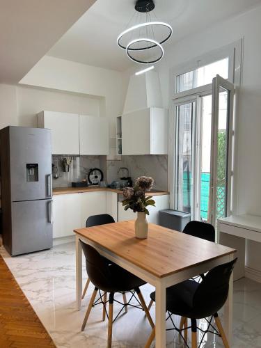une cuisine avec une table en bois et des chaises noires dans l'établissement Suite HISPANIA FSHH, à Nice