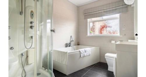 a white bathroom with a tub and a sink at Cullentra House in Cushendall